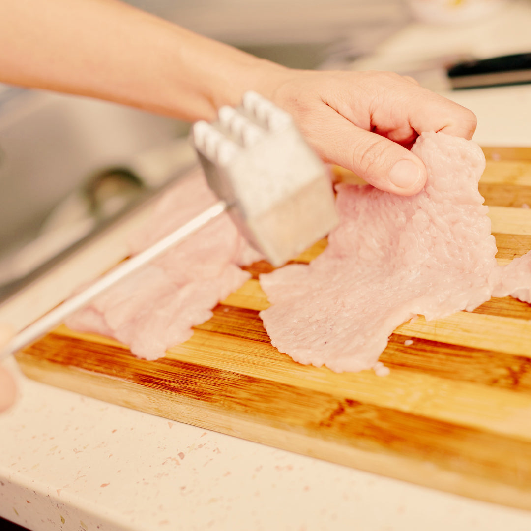 Pounding chicken on cutting board