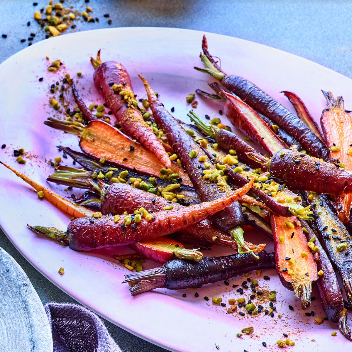 Purple and orange carrots with seasoning on large serving dish