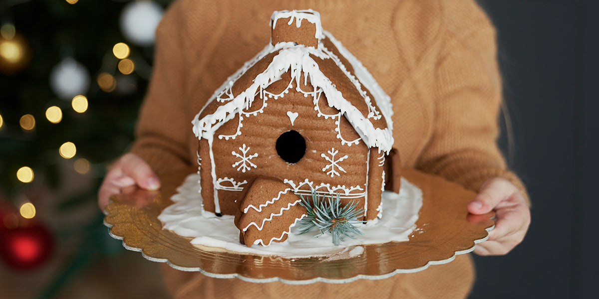 Young child holding gingerbread house on a plate