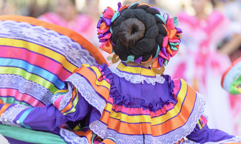 The back of a girl dressed in colorful indigenous clothing as part of a festival for Hispanic Heritage Month