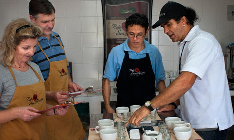A man explains different coffee beans in a tasting with 3 people in aprons