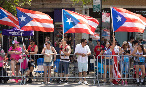 People waving flags of Puerto Rico while they wait for a procession to start as part of Hispanic Heritage Month