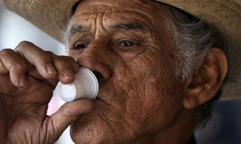An older Cuban man, wearing a hat, drinks cafecito