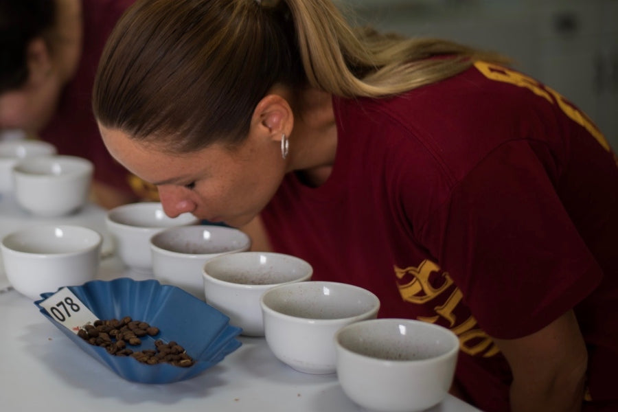 A woman smells different coffee beans