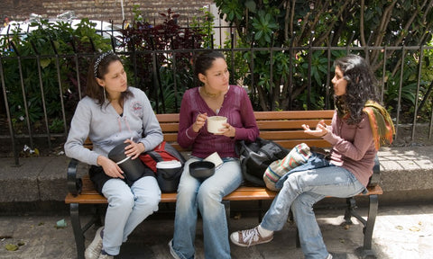 Three Latina women talking on a bench