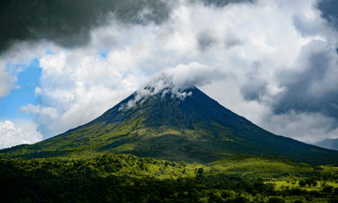 Volcano Arenal in Costa Rica spouting ash into a cloud-scattered sky