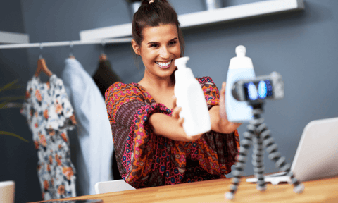 A woman films herself in her home, showing cleaning products to the camera