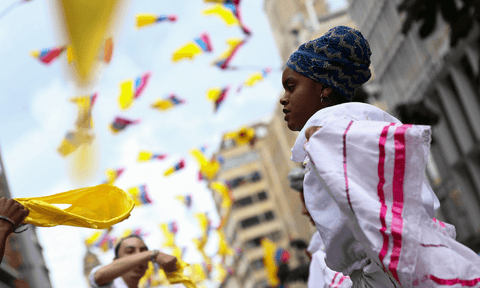Mujer celebra el Día de la Independencia de Colombia en la calle. Muchas pequeñas banderas colombianas ondean por encima