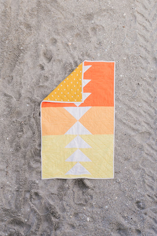 Orange and yellow children’s quilt on a beach