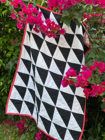 black and white custom, handmade baby quilt hanging by pink flowers