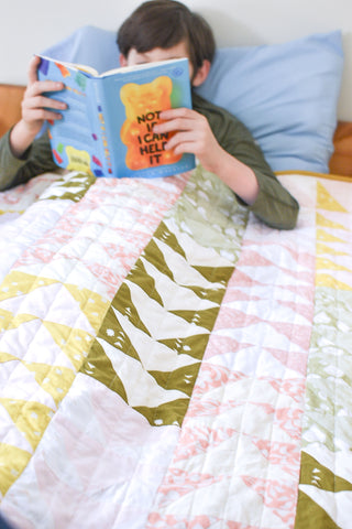 Boy snuggling under quilt reading