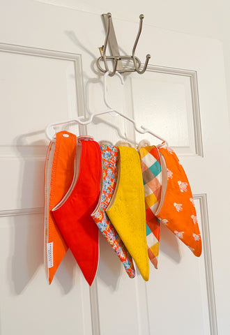 Baby bibs hanging on a hanger on the back of a door