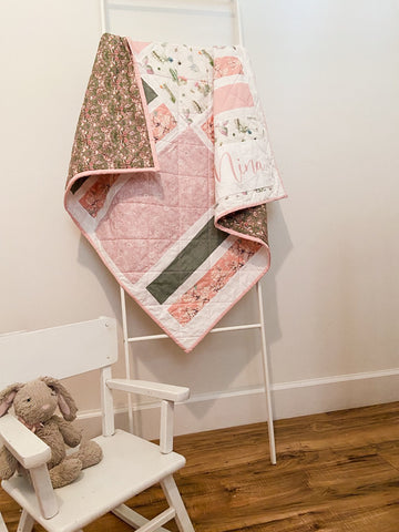 baby girl quilt hanging on blanket ladder in nursery