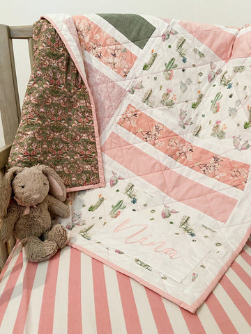 baby quilt hanging in crib with stuffed bunny