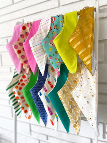 baby bibs hanging on ladder in front of white wall