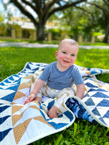 baby boy sitting on his polar bear quilt outside