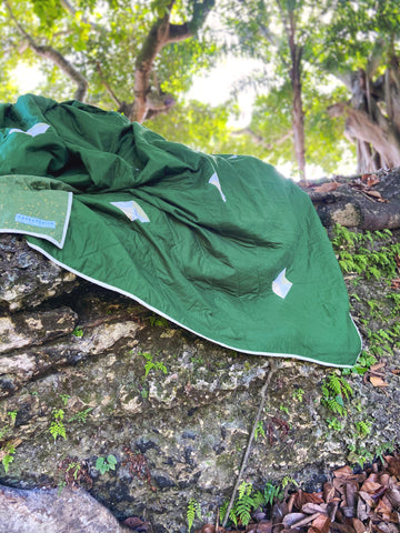 custom king sized green quilt sitting on a rock