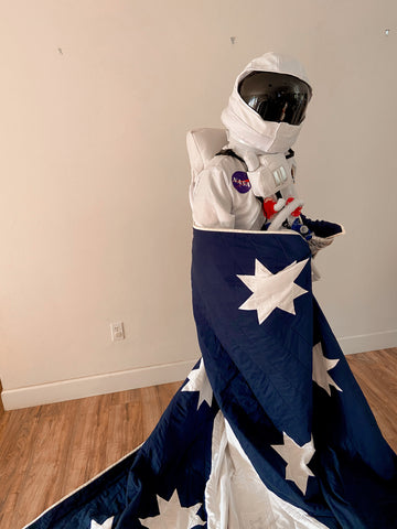 man in astronaut costume wrapped in custom kid's rocket ship quilt