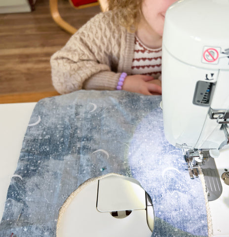 toddler helping sew a blue baby bib