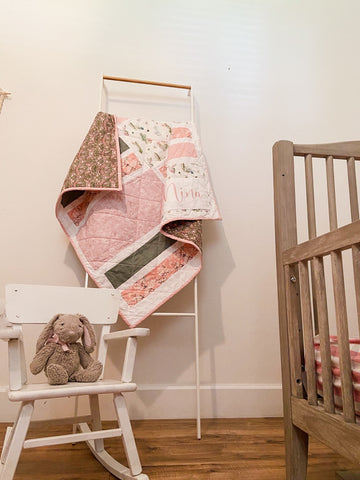 baby girl quilt hanging in baby nursery