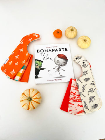 orange baby bib sets shown with a children's halloween themed book