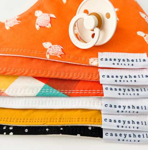 stack of baby bibs with a pacifier on top