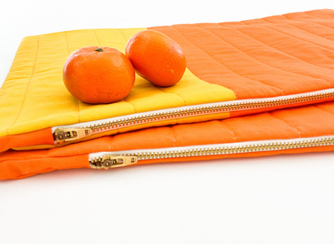 orange and yellow quilted pillows with two oranges on top
