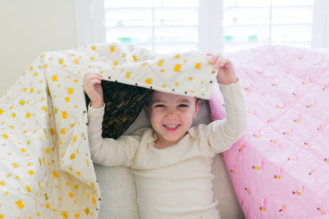 little boy peeking out underneath quilt