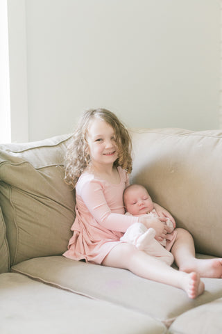 toddler holding newborn sister