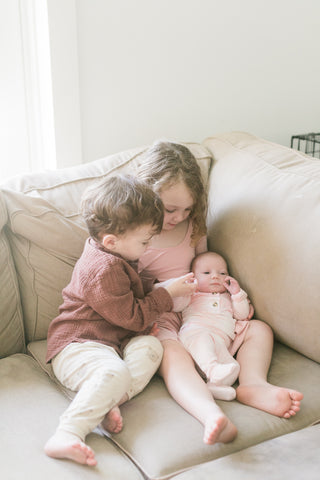 toddlers holding newborn baby sister