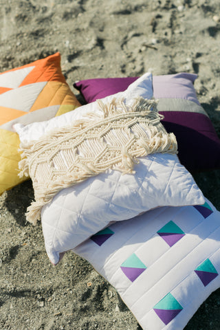 four quilted pillows in a pile on the beach