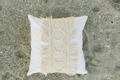 quilted pillow with macrame displayed on beach