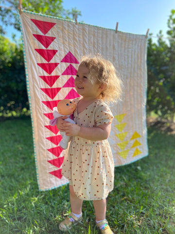 toddler girl standing in front of quilt outside