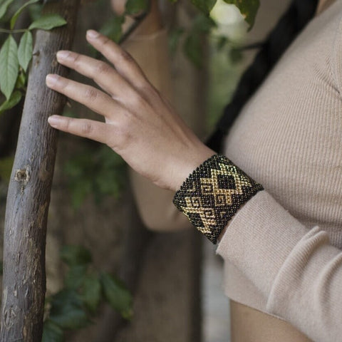 woman wearing Grecian Gold mosaic black gold beaded bracelet cuff in forest