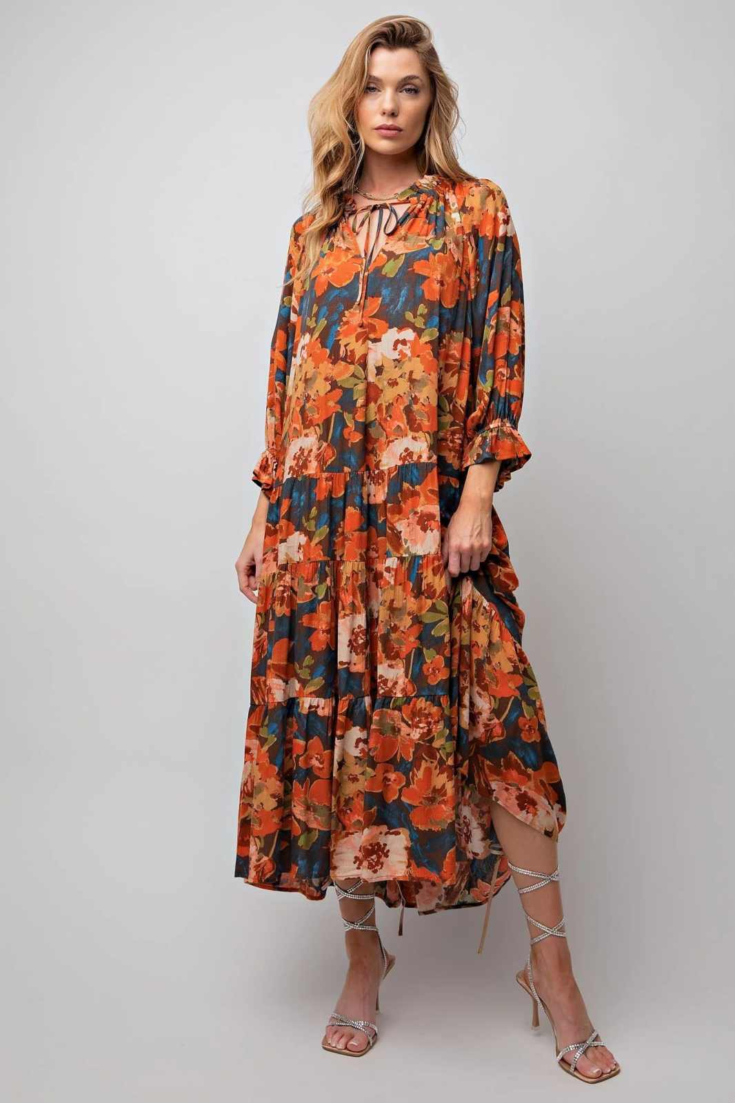 Woman wearing orange and blue springtime floral dress and silver heels