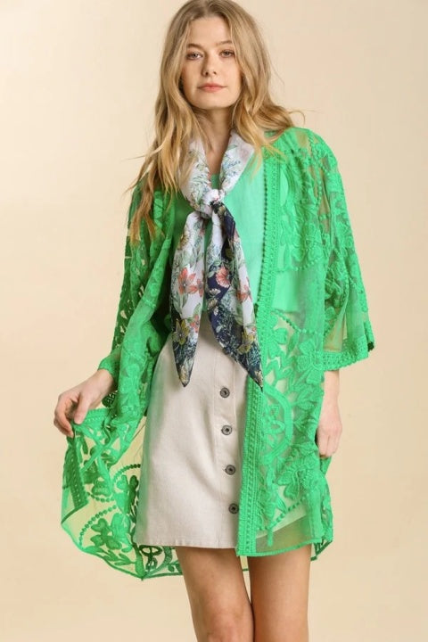 Woman wearing green lace kimono with tan skirt, green shirt, and floral scarf