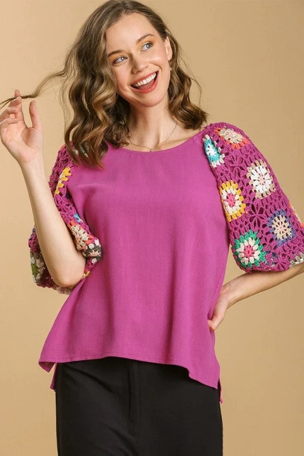 Woman wearing pink shirts with knitted floral sleeves and black pants