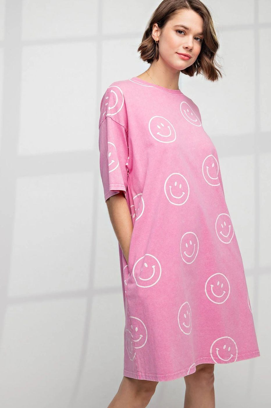 Woman wears pink short-sleeve dress with smiley faces