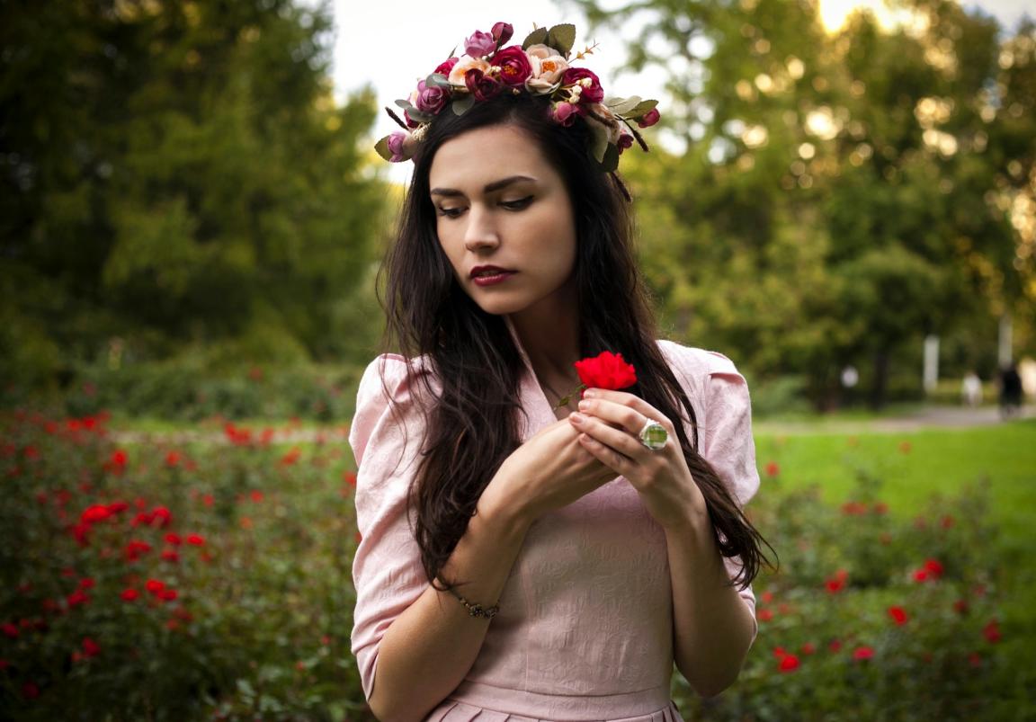 Woman wearing a springtime dress holds a red flower