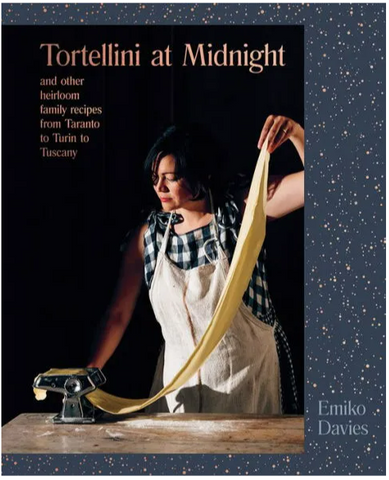 Author Emiko Davies pulling pasta through a mechanical roller, black background, and navy book board.  It's a beautiful book.
