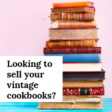 Stack of vintage books on a blue wooden table with a pink background