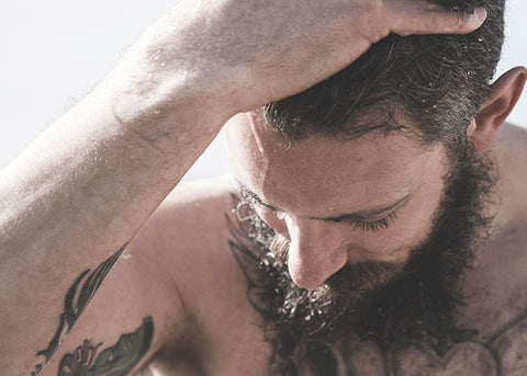 man washing his beard with beard shampoo in the shower