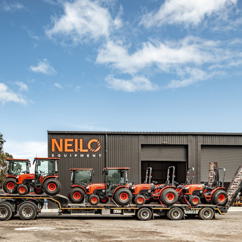 8 red kubota tractors on a larger trailer 