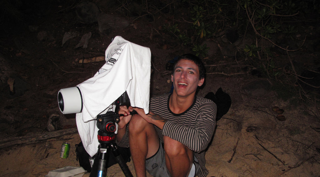 man in the dark filming surfing on the beach