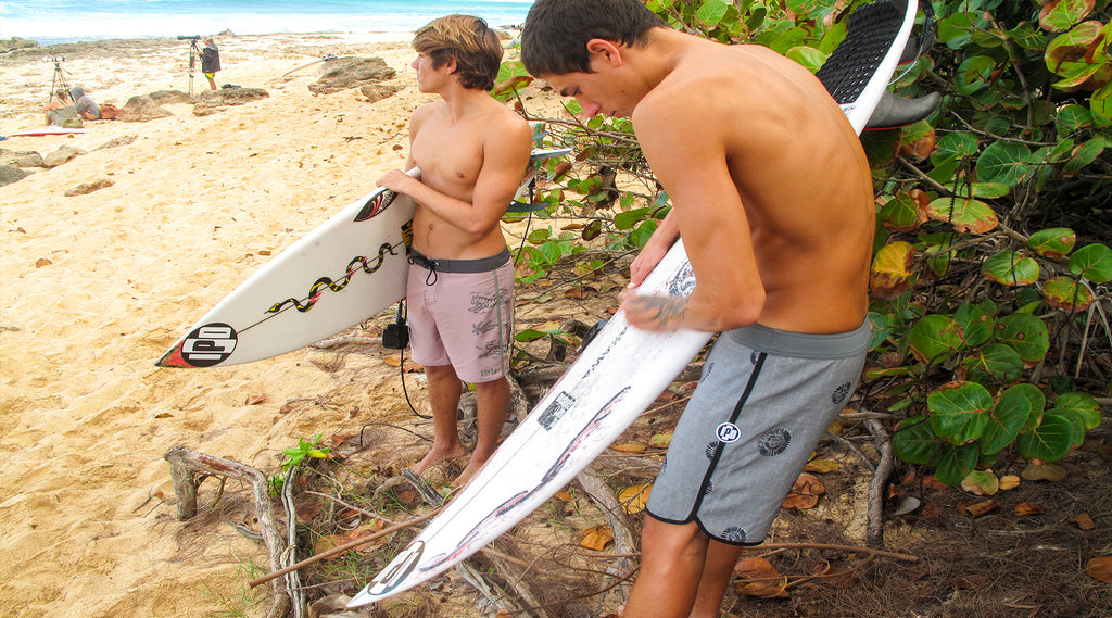 men waxing surfboards on beach