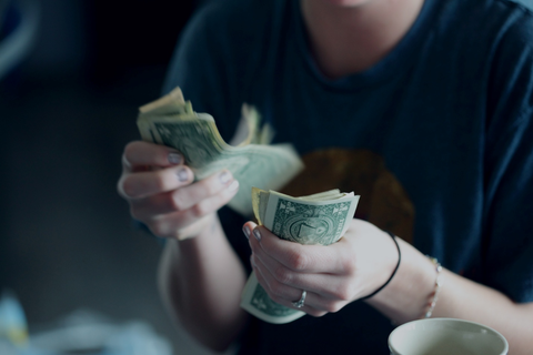 A woman counting dollars for her next greenhouse project