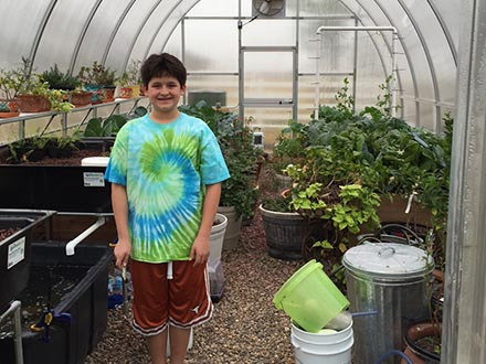 A boy standing inside a Riga greenhouse