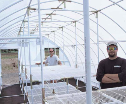 Two men assembling a Solexx greenhouse with an aluminum frame