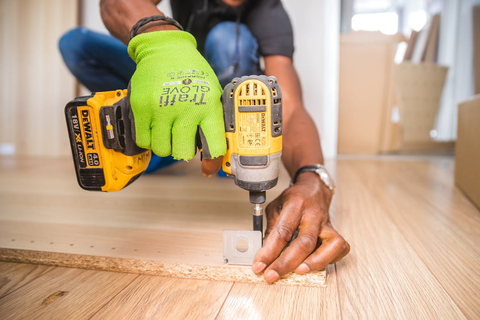 A person making a wooden panel for a greenhouse foundation