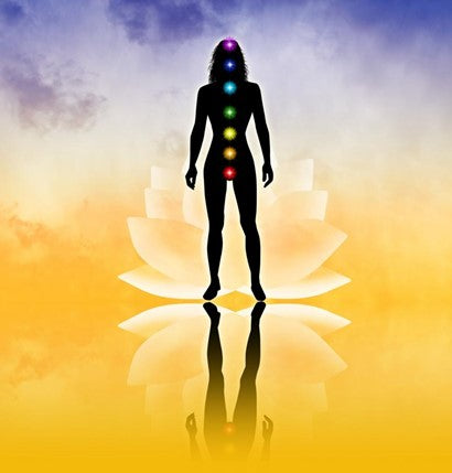 A woman’s silhouette standing on a gradient background with a lotus flower, colored chakra balls highlighted on her body.